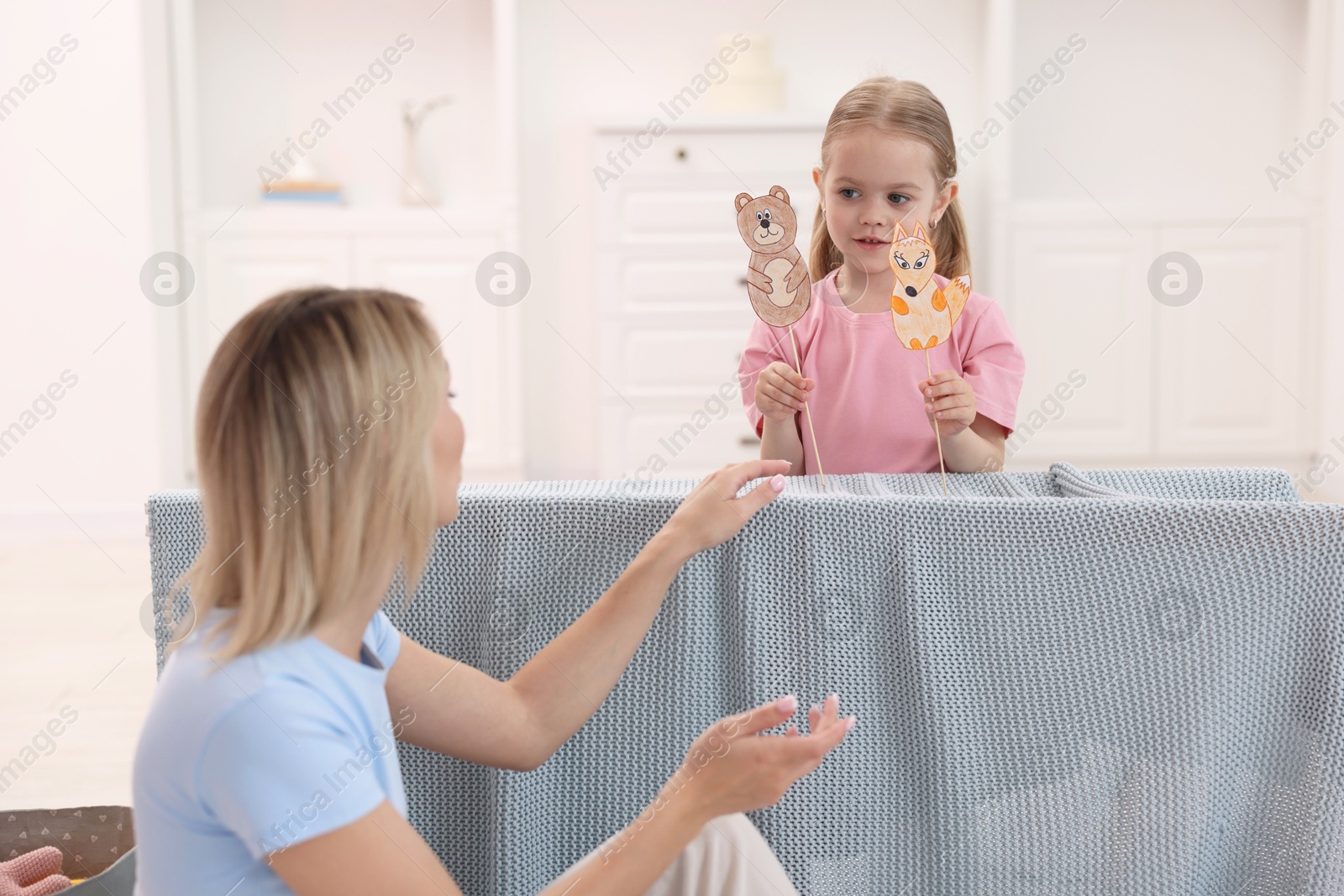 Photo of Puppet theatre. Girl performing show to her mother at home