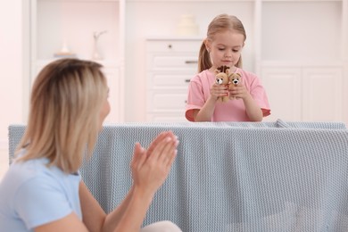 Puppet theatre. Girl performing show to her mother at home