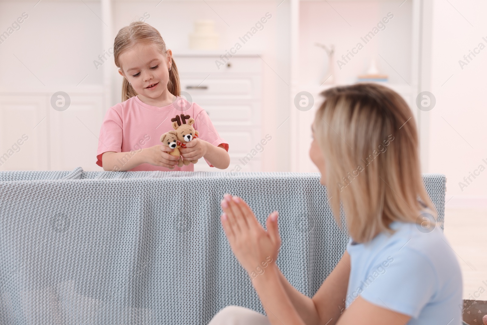 Photo of Puppet theatre. Girl performing show to her mother at home