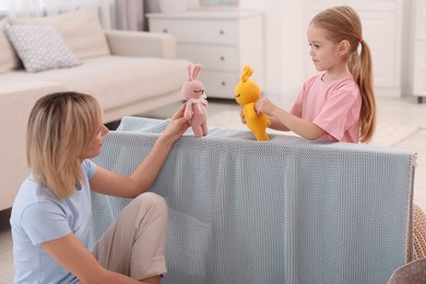 Photo of Puppet theatre. Mother and daughter performing show at home