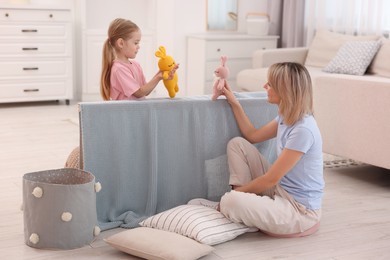 Photo of Puppet theatre. Mother and daughter performing show at home