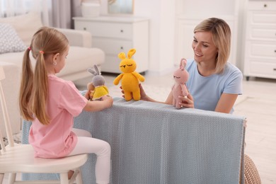 Puppet theatre. Smiling mother and daughter performing show at home