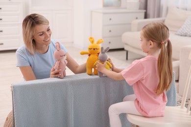 Photo of Puppet theatre. Smiling mother and daughter performing show at home