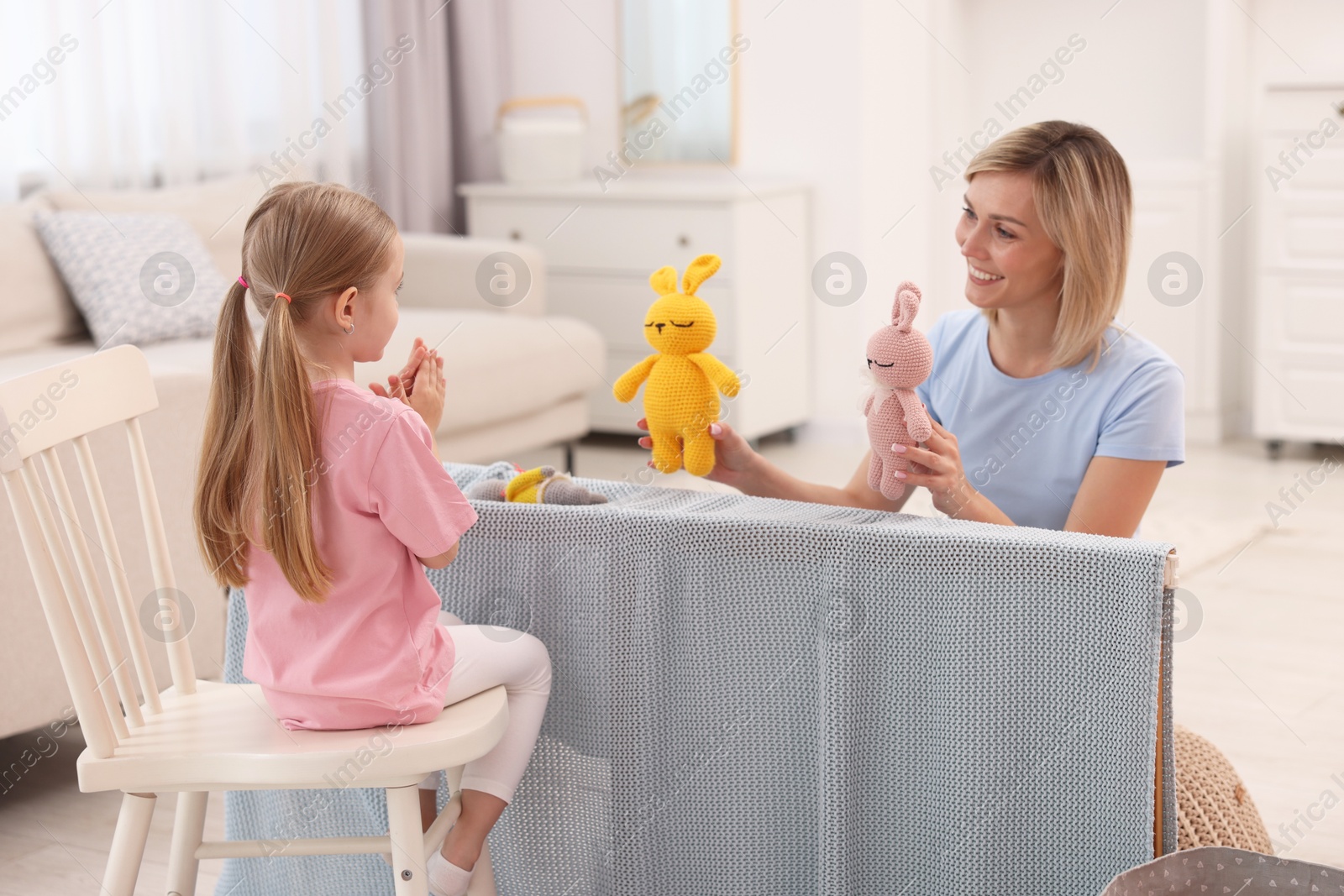 Photo of Puppet theatre. Smiling mother and daughter performing show at home