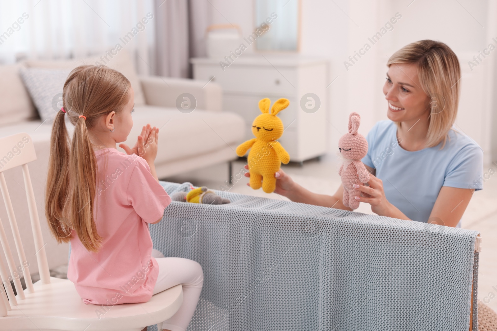 Photo of Puppet theatre. Smiling mother and daughter performing show at home