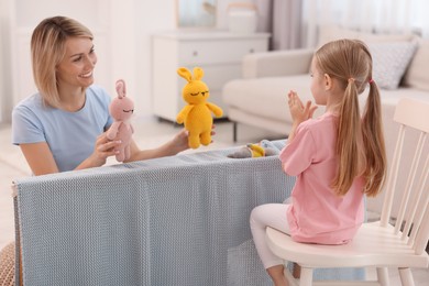 Puppet theatre. Smiling mother and daughter performing show at home