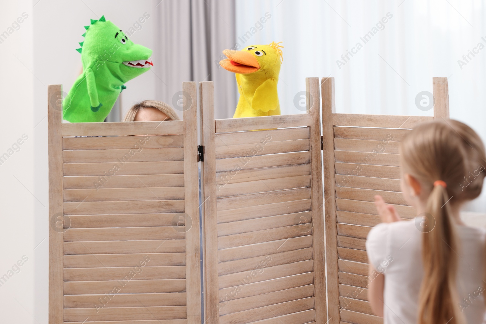 Photo of Girl watching puppet theatre at home, back view