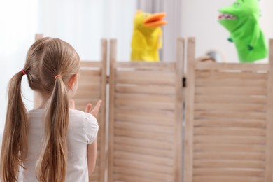 Girl watching puppet theatre at home, back view