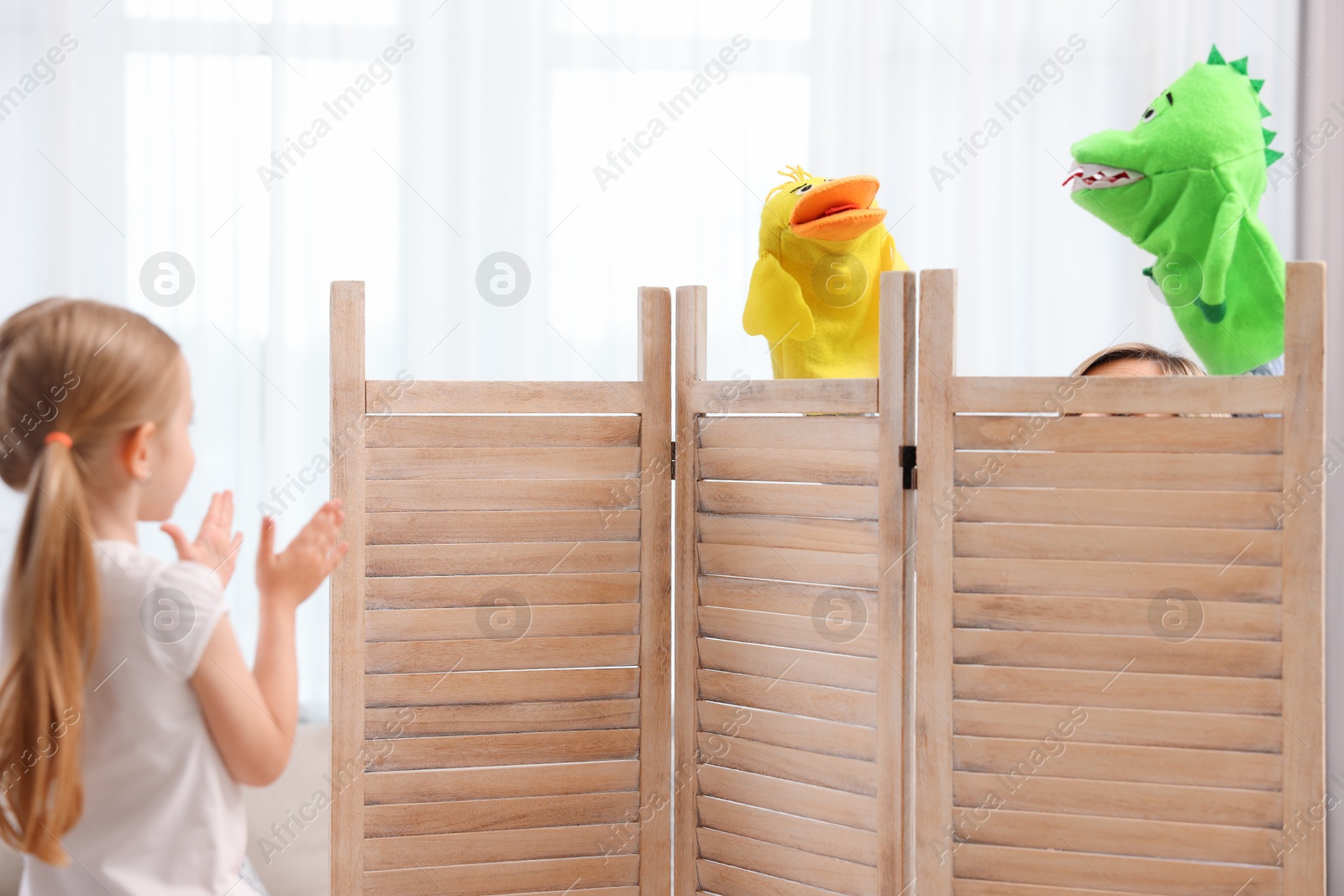 Photo of Girl watching puppet theatre at home, back view