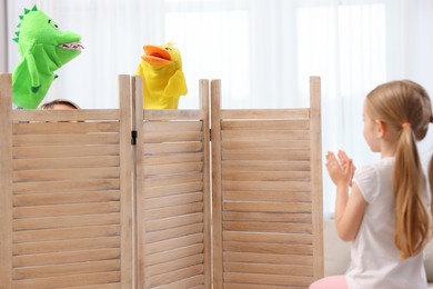 Girl watching puppet theatre at home, back view