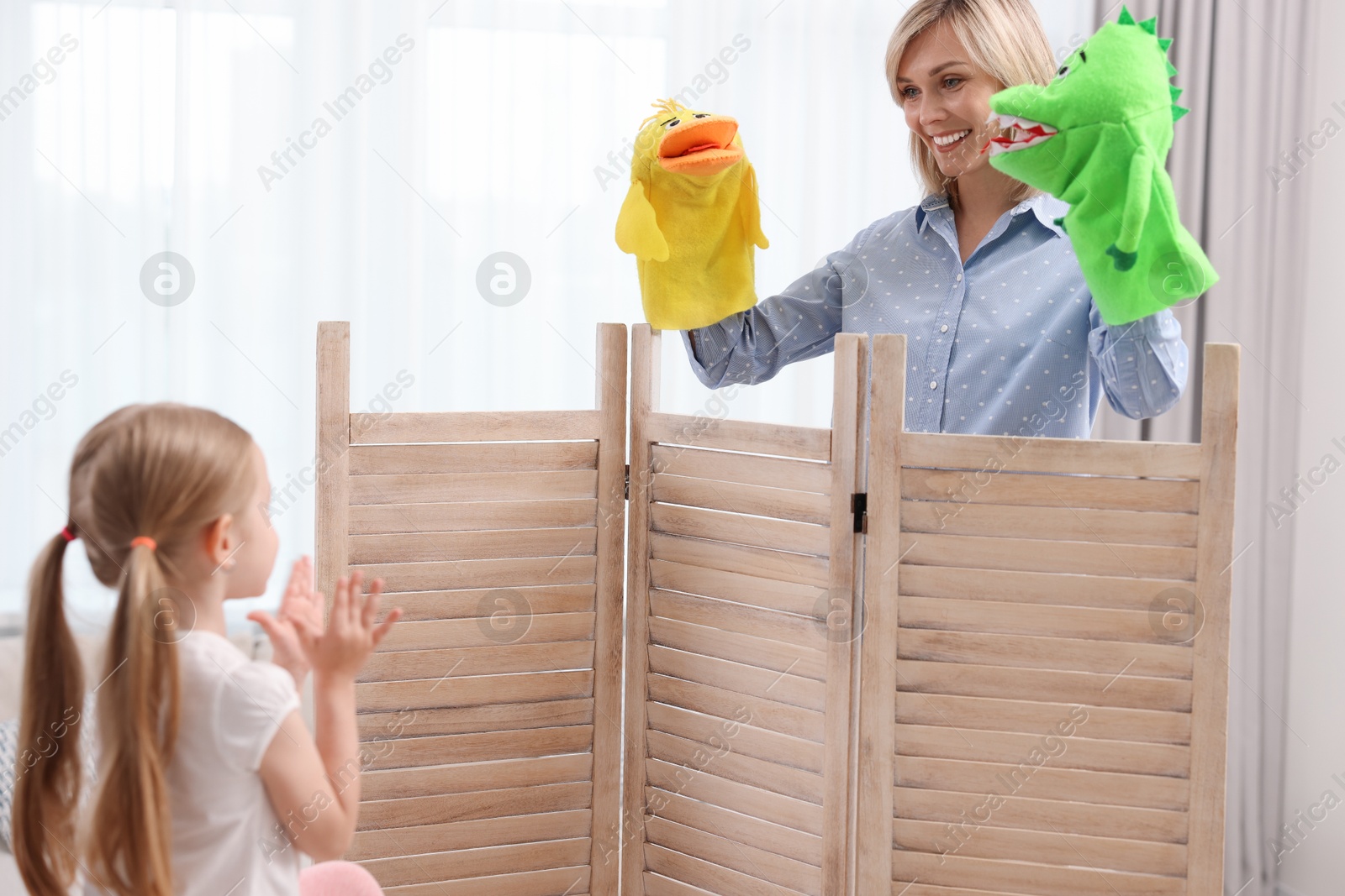 Photo of Puppet theatre. Smiling mother performing show to her daughter at home