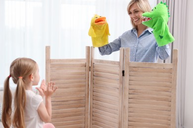 Puppet theatre. Smiling mother performing show to her daughter at home