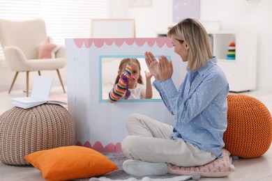 Puppet theatre. Girl performing show to her mother at home