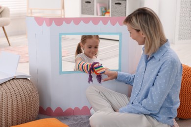 Photo of Puppet theatre. Mother and daughter performing show at home