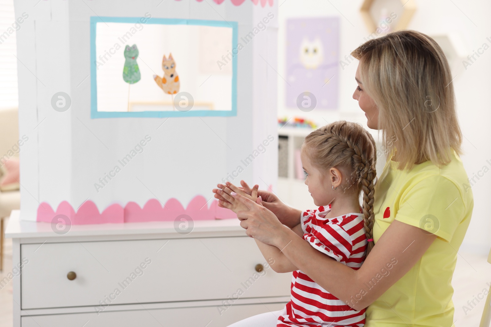 Photo of Mother and daughter watching puppet theatre at home