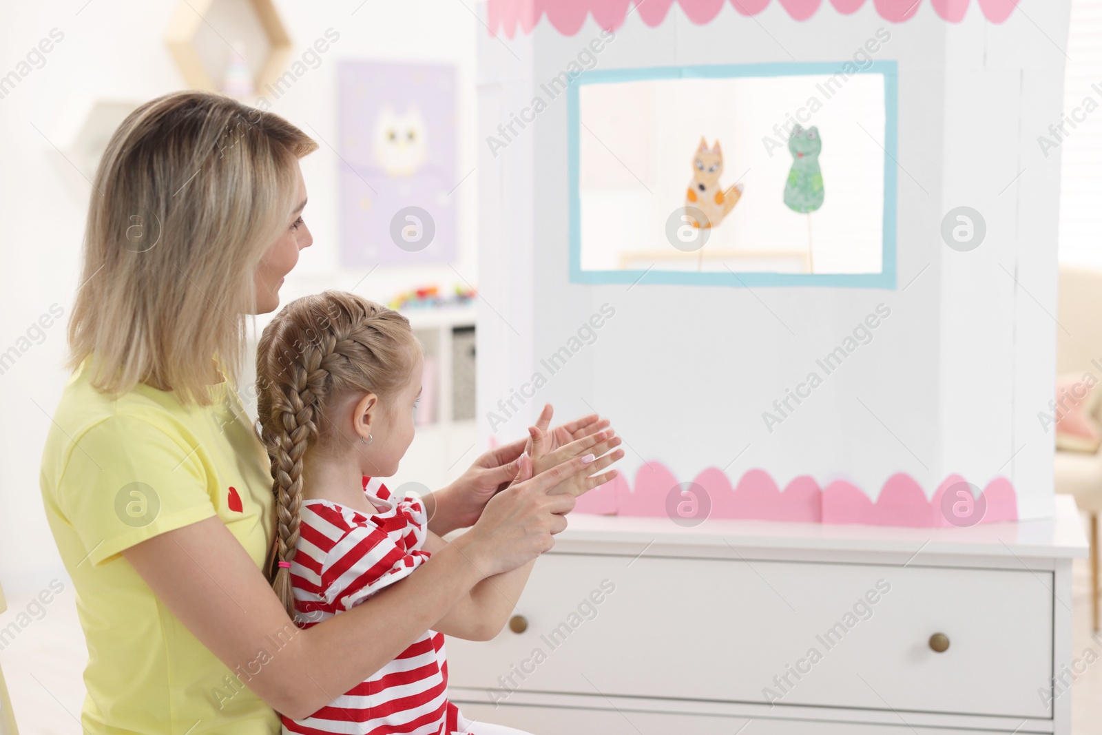 Photo of Mother and daughter watching puppet theatre at home