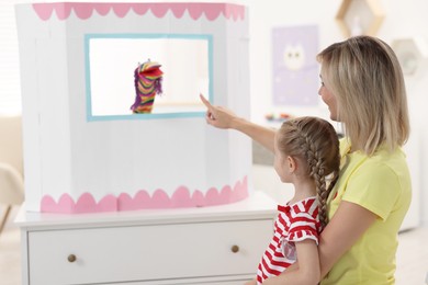 Mother and daughter watching puppet theatre at home