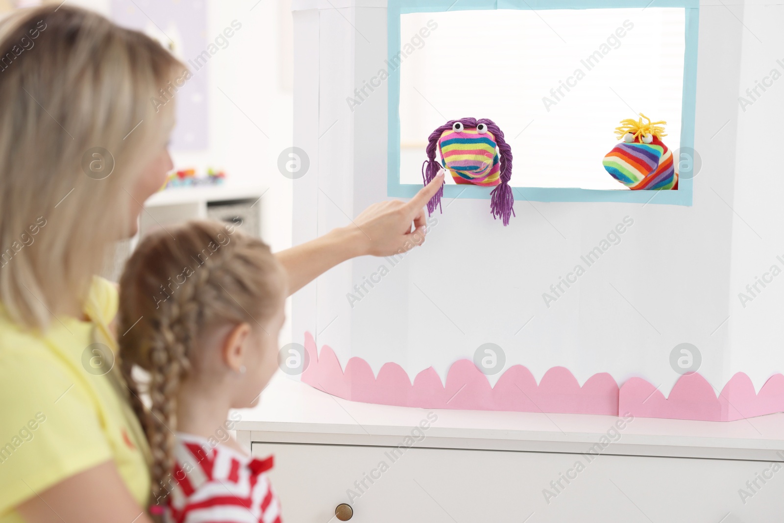 Photo of Mother and daughter watching puppet theatre at home