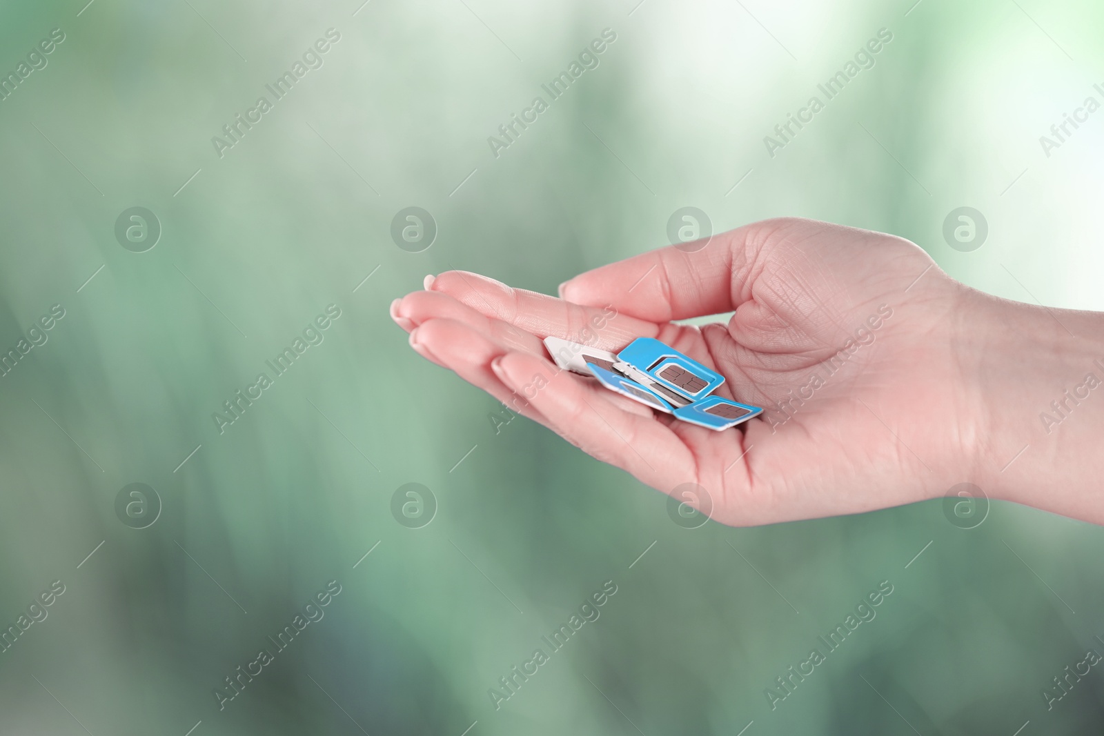 Photo of Woman holding SIM cards on blurred background, closeup