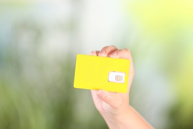 Photo of Woman holding SIM card on blurred background, closeup