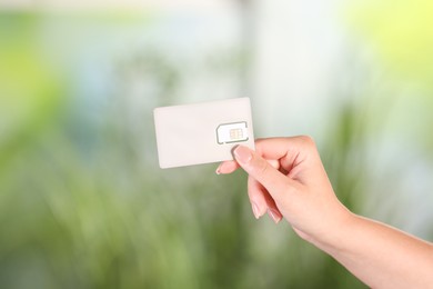 Photo of Woman holding SIM card on blurred background, closeup