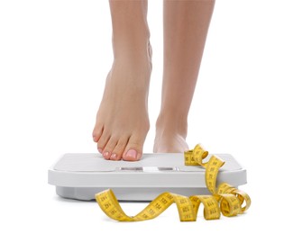 Diet and weight loss concept. Woman on floor scale and measuring tape against white background, closeup