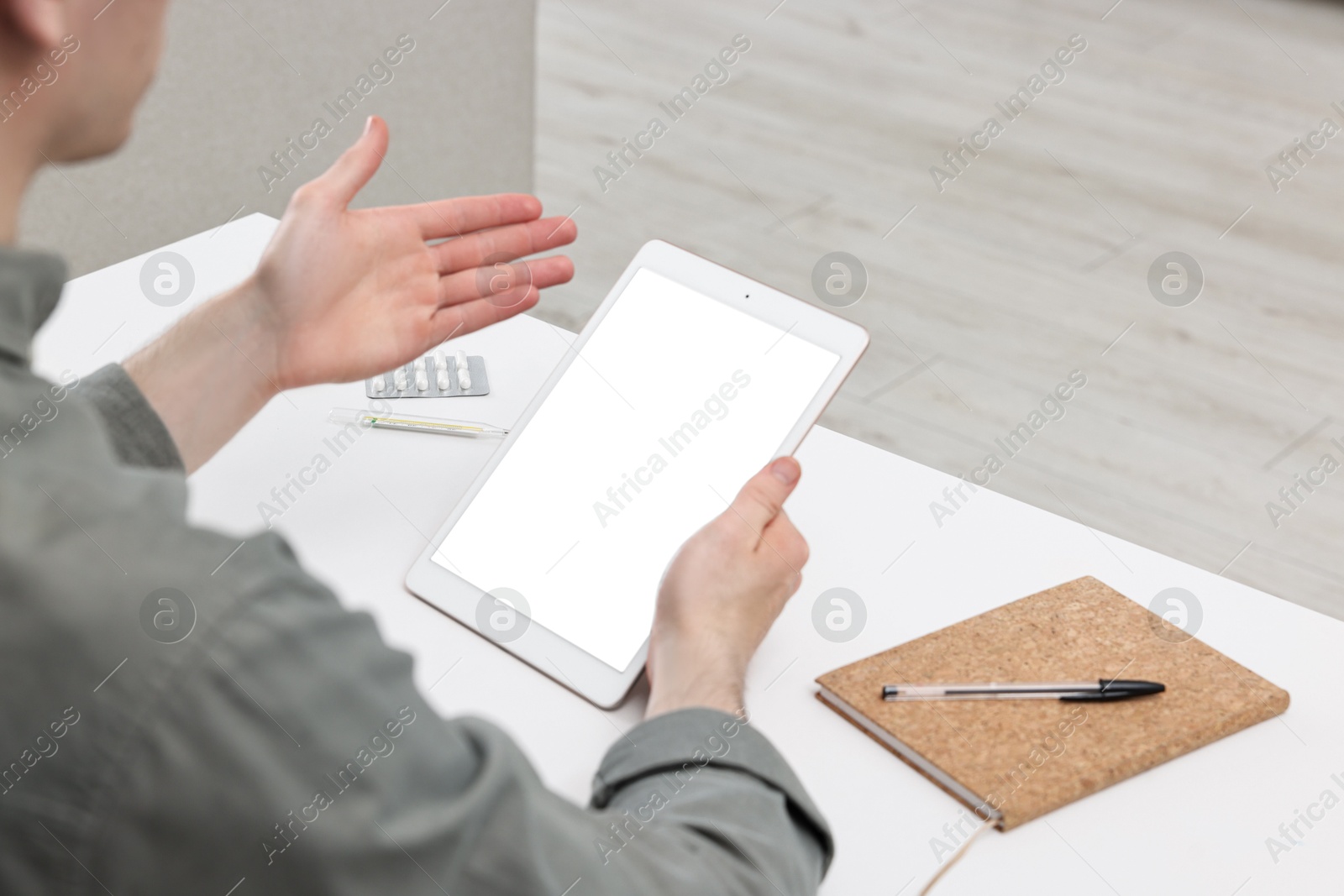 Photo of Sick man having online consultation with doctor via tablet at home, closeup