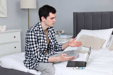 Sick man having online consultation with doctor via laptop at home