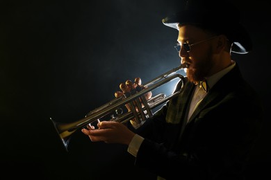 Photo of Professional musician playing trumpet on black background