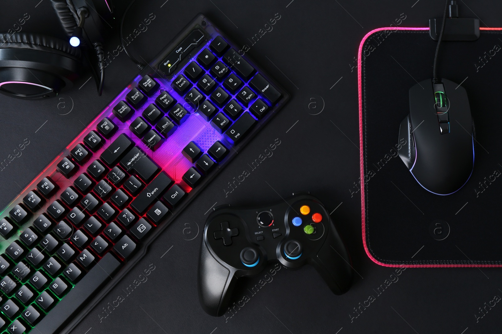 Photo of Computer mouse, RGB keyboard, game controller and headset on black background, flat lay