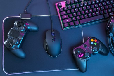 Photo of Computer mouse, RGB keyboard and game controllers on black background, top view