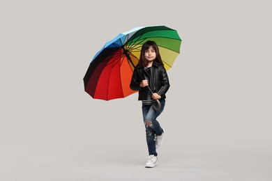 Photo of Cute little girl with colorful umbrella on light grey background