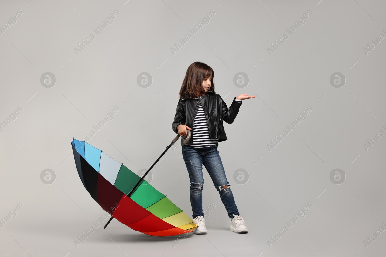 Photo of Cute little girl with colorful umbrella on light grey background