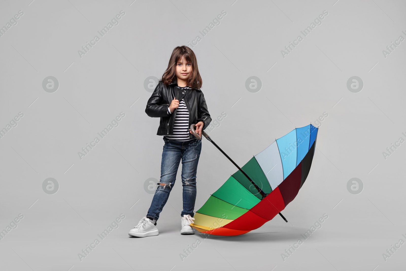 Photo of Cute little girl with colorful umbrella on light grey background