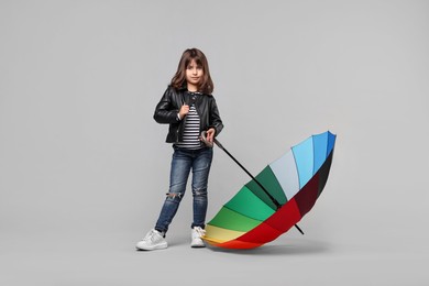 Photo of Cute little girl with colorful umbrella on light grey background