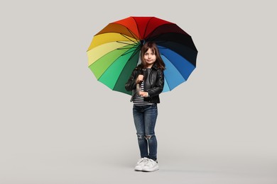 Photo of Cute little girl with colorful umbrella on light grey background