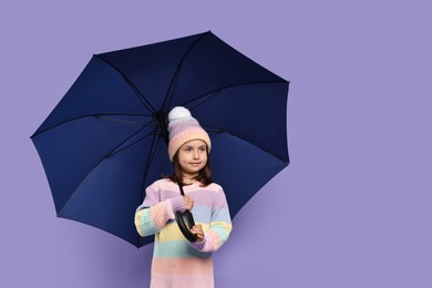 Cute little girl with blue umbrella on purple background. Space for text