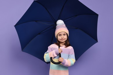 Photo of Cute little girl with blue umbrella on purple background