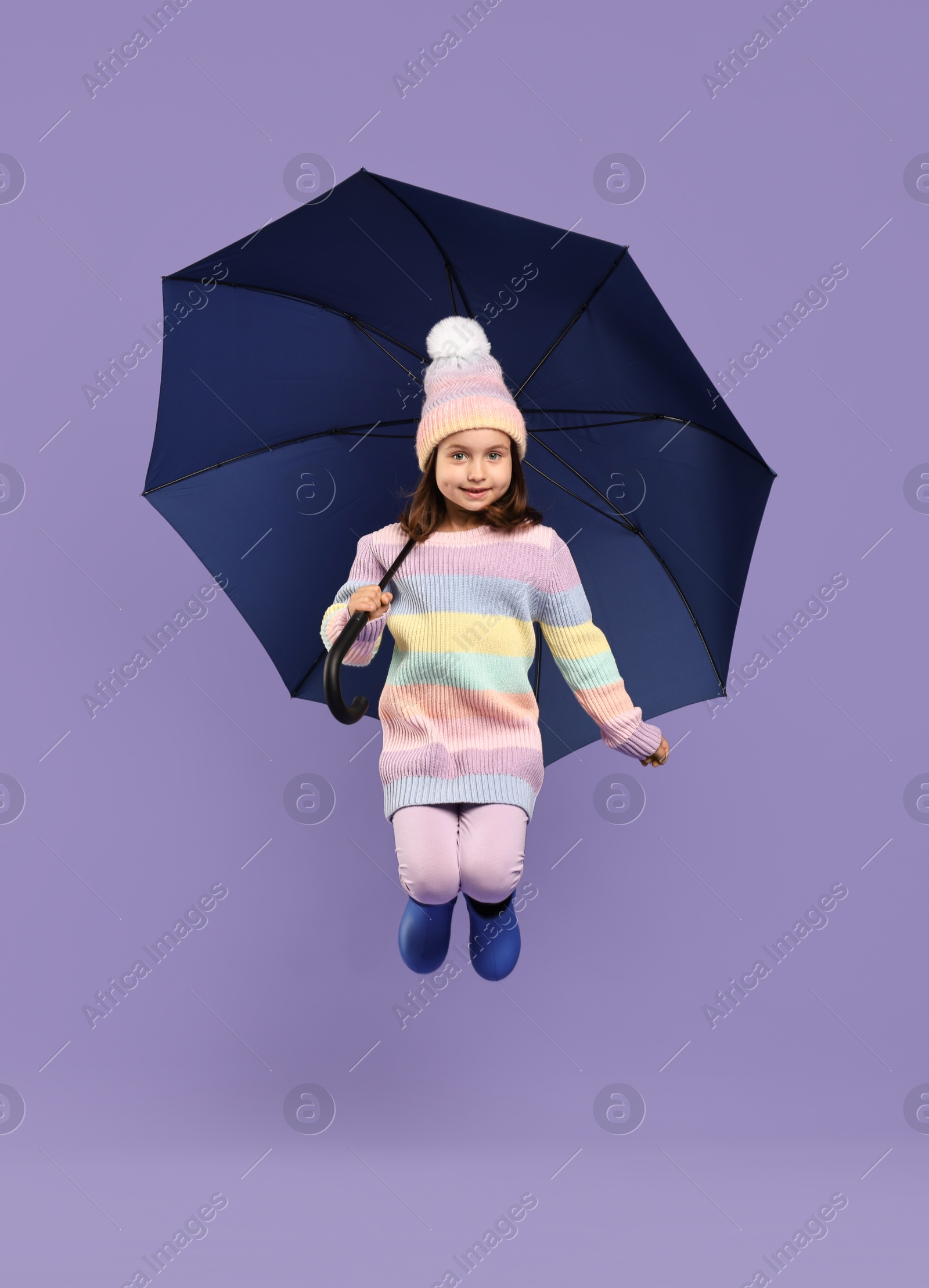 Photo of Cute little girl with blue umbrella on purple background