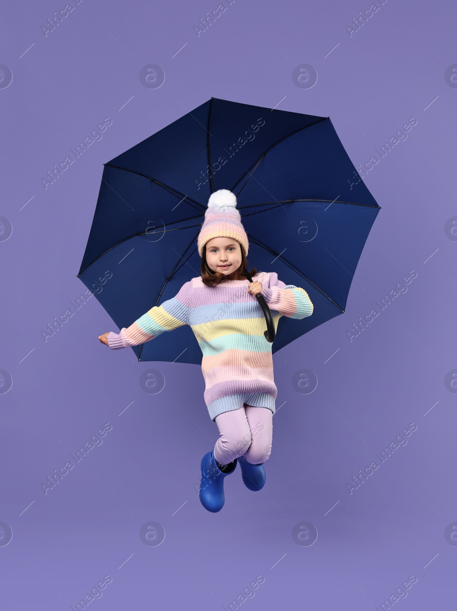 Photo of Cute little girl with blue umbrella on purple background