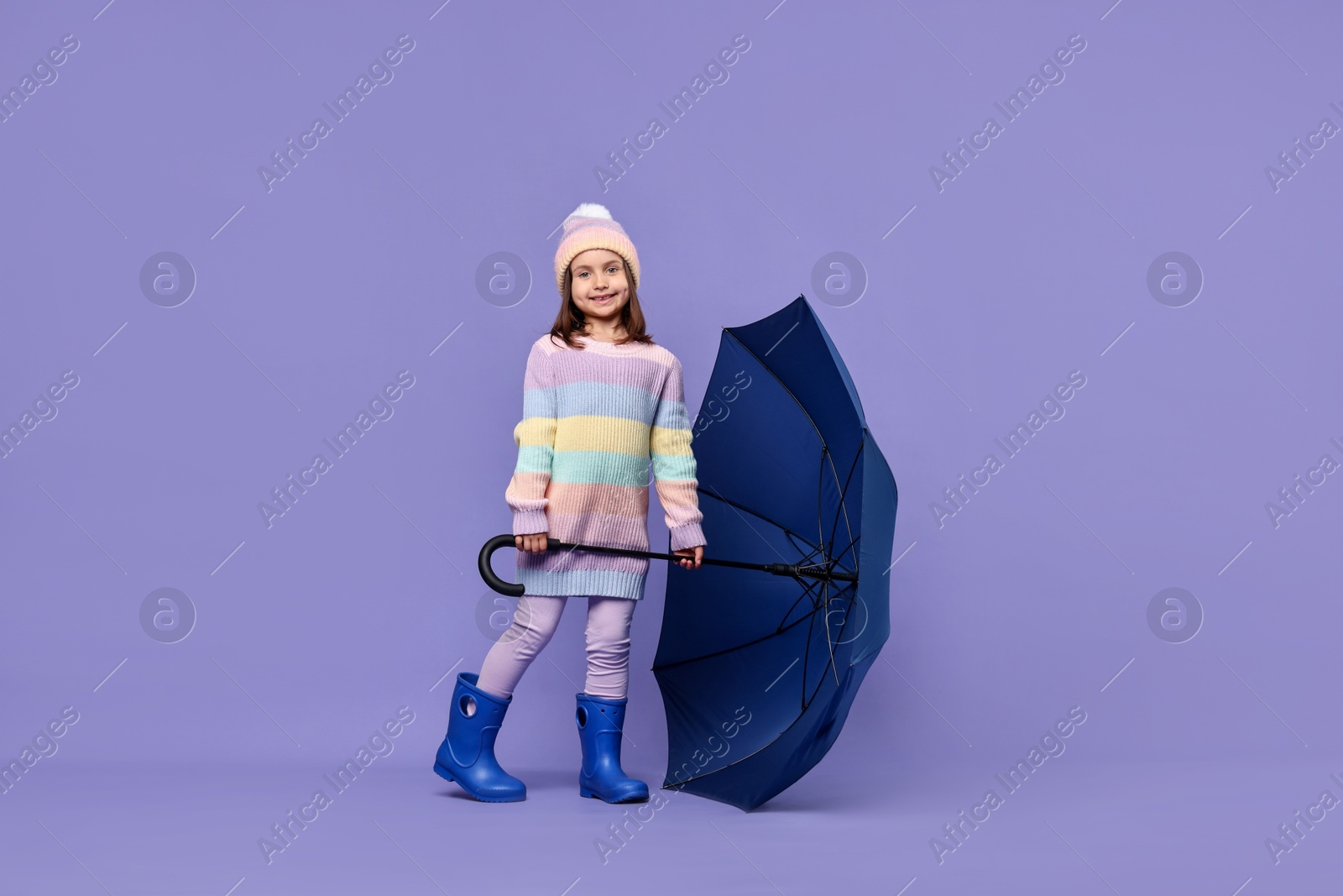 Photo of Cute little girl with blue umbrella on purple background