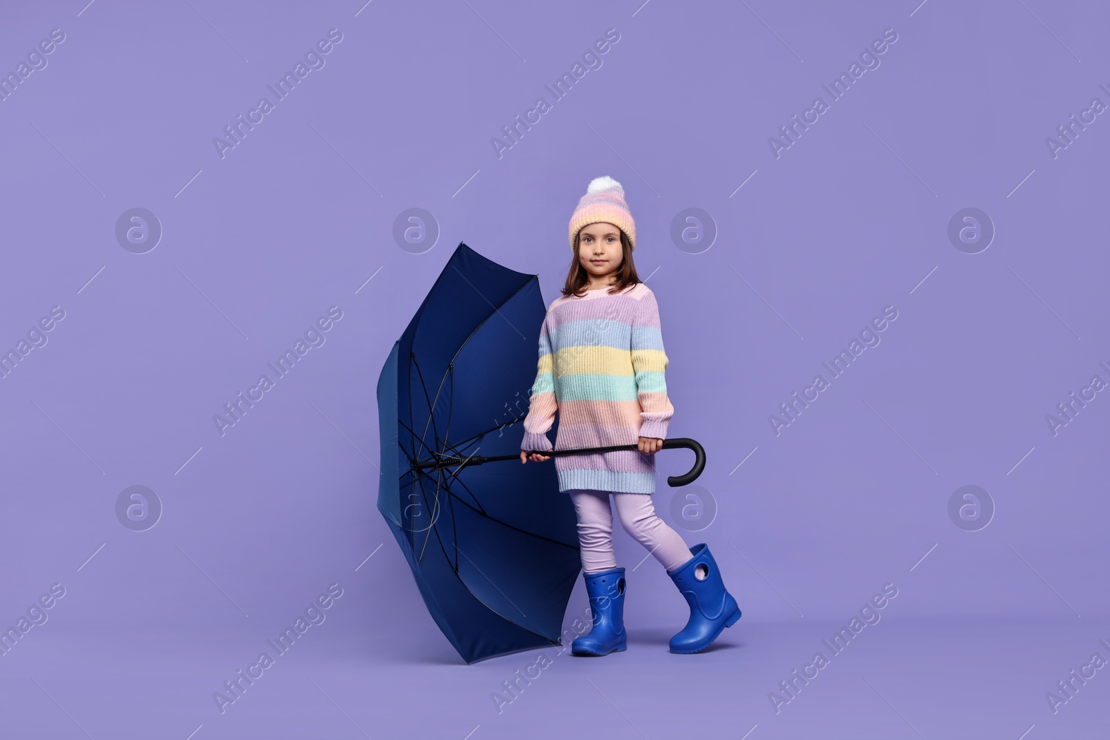 Photo of Cute little girl with blue umbrella on purple background