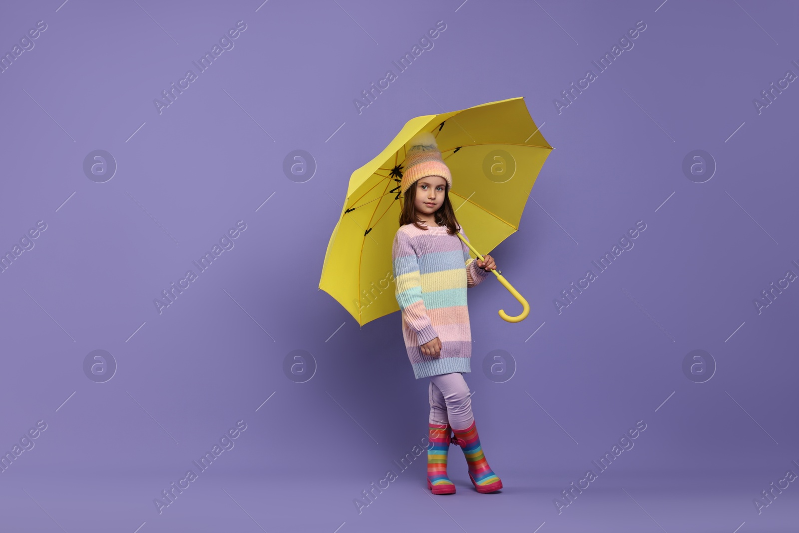 Photo of Cute little girl with yellow umbrella on purple background