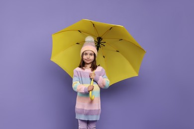 Photo of Cute little girl with yellow umbrella on purple background