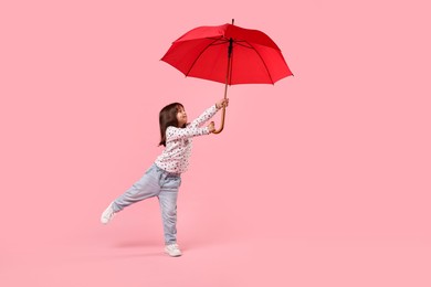 Photo of Cute little girl with red umbrella on pink background