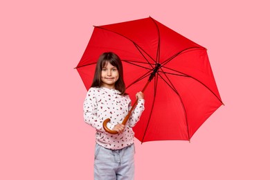 Photo of Cute little girl with red umbrella on pink background