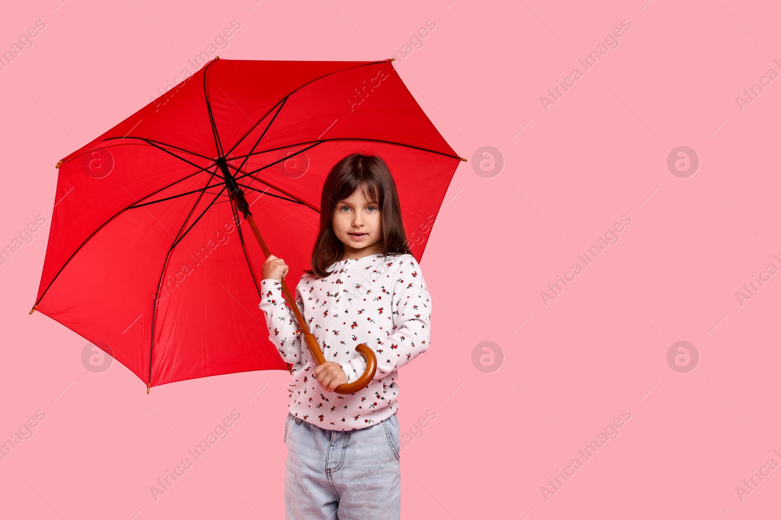 Photo of Cute little girl with red umbrella on pink background. Space for text