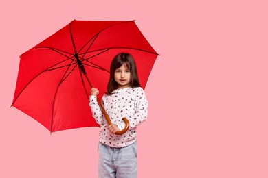 Photo of Cute little girl with red umbrella on pink background. Space for text