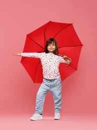 Photo of Cute little girl with red umbrella on pink background