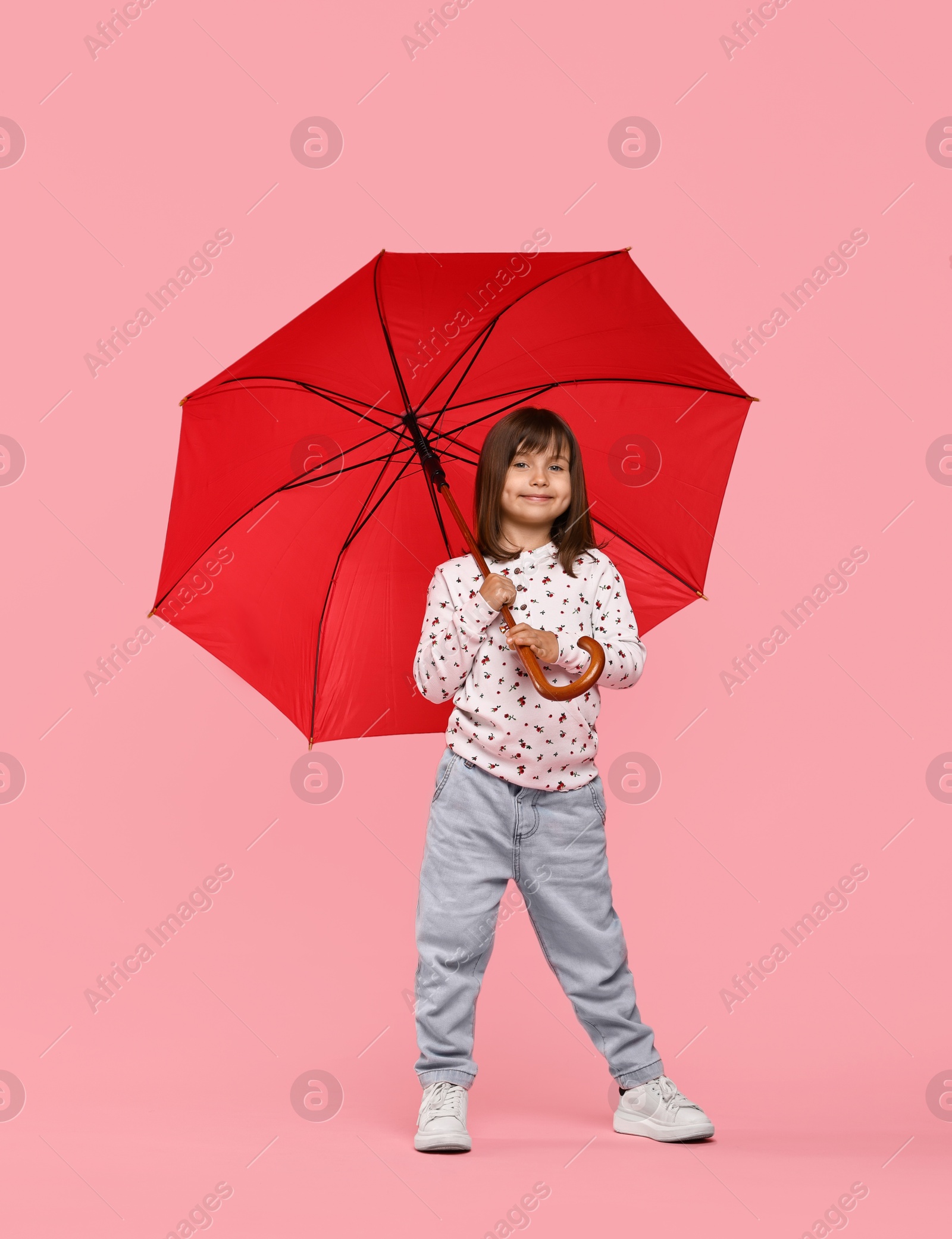 Photo of Cute little girl with red umbrella on pink background